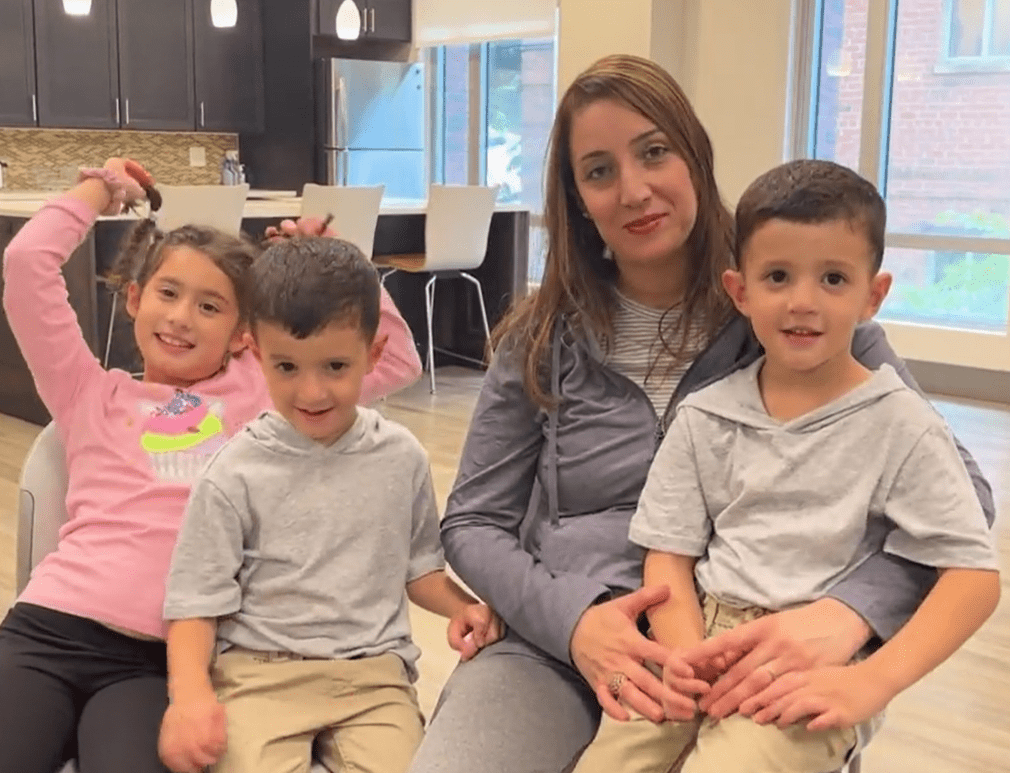 Woman sitting smiling, with three children, one of them on her lap.