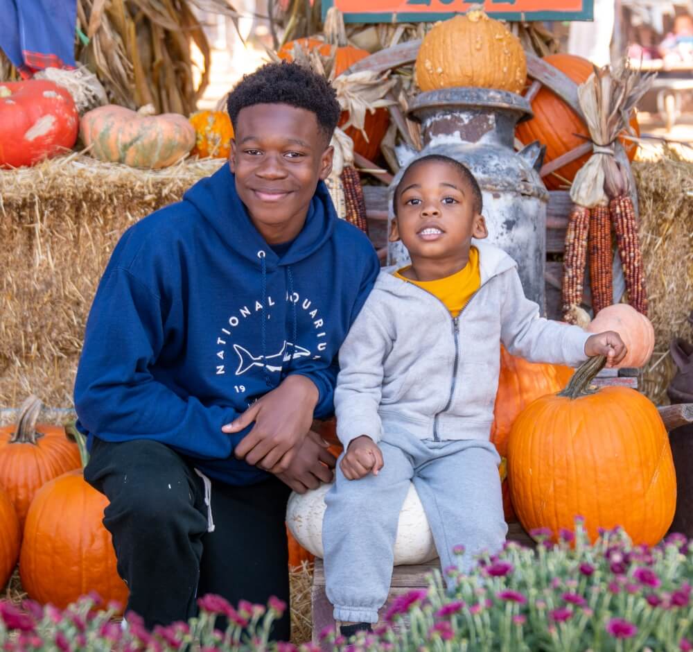 True-Ground-Ways-to-Give-Donor-FAQs@2x Two boys sitting with pumpkins and autumn decorations