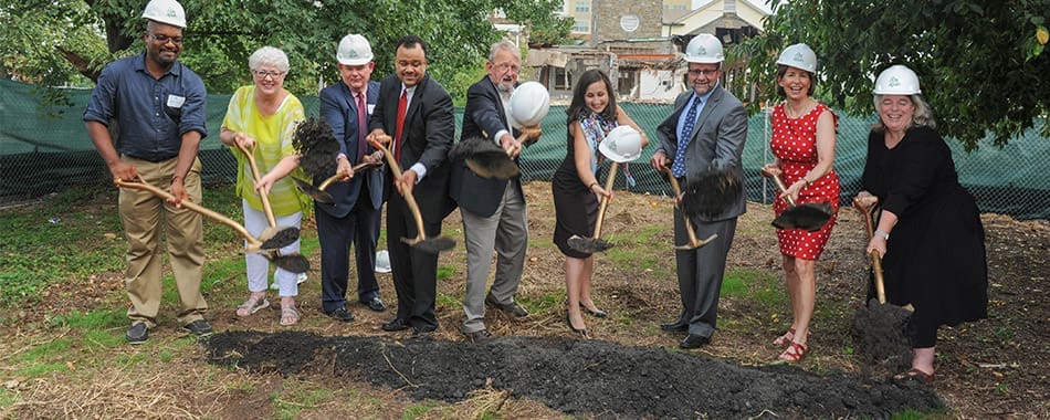 Group of people in hard hats breaking ground at Gilliam Place groundbreaking ceremony.
