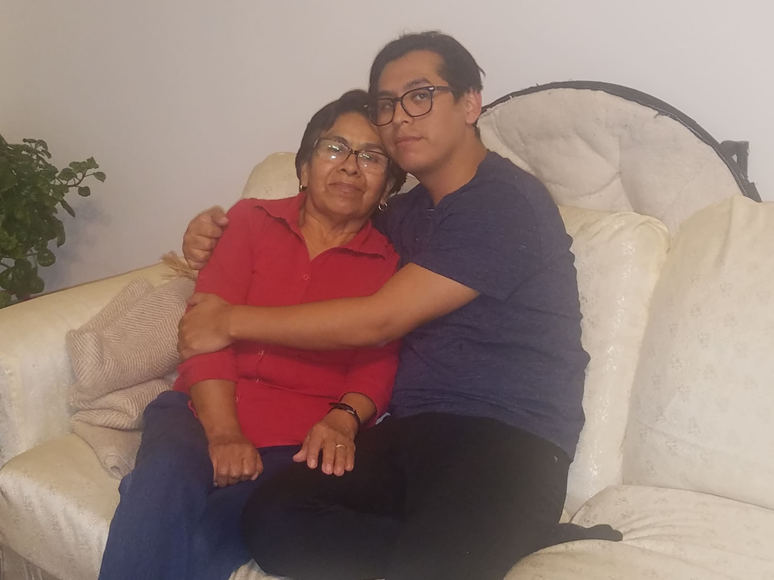 Young man hugging an older woman on a couch, expressing family warmth