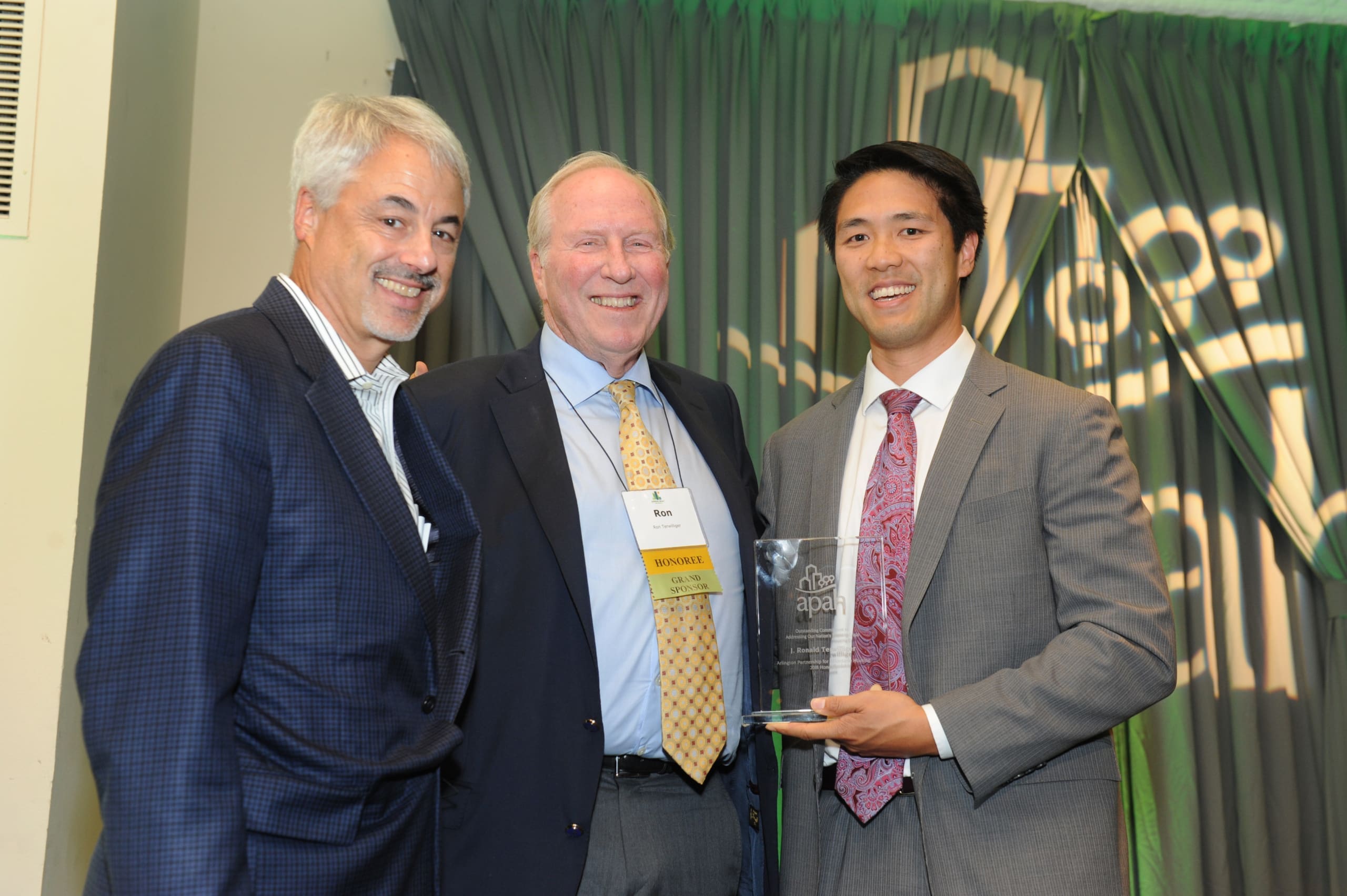 Three men posing with an award at a gala event