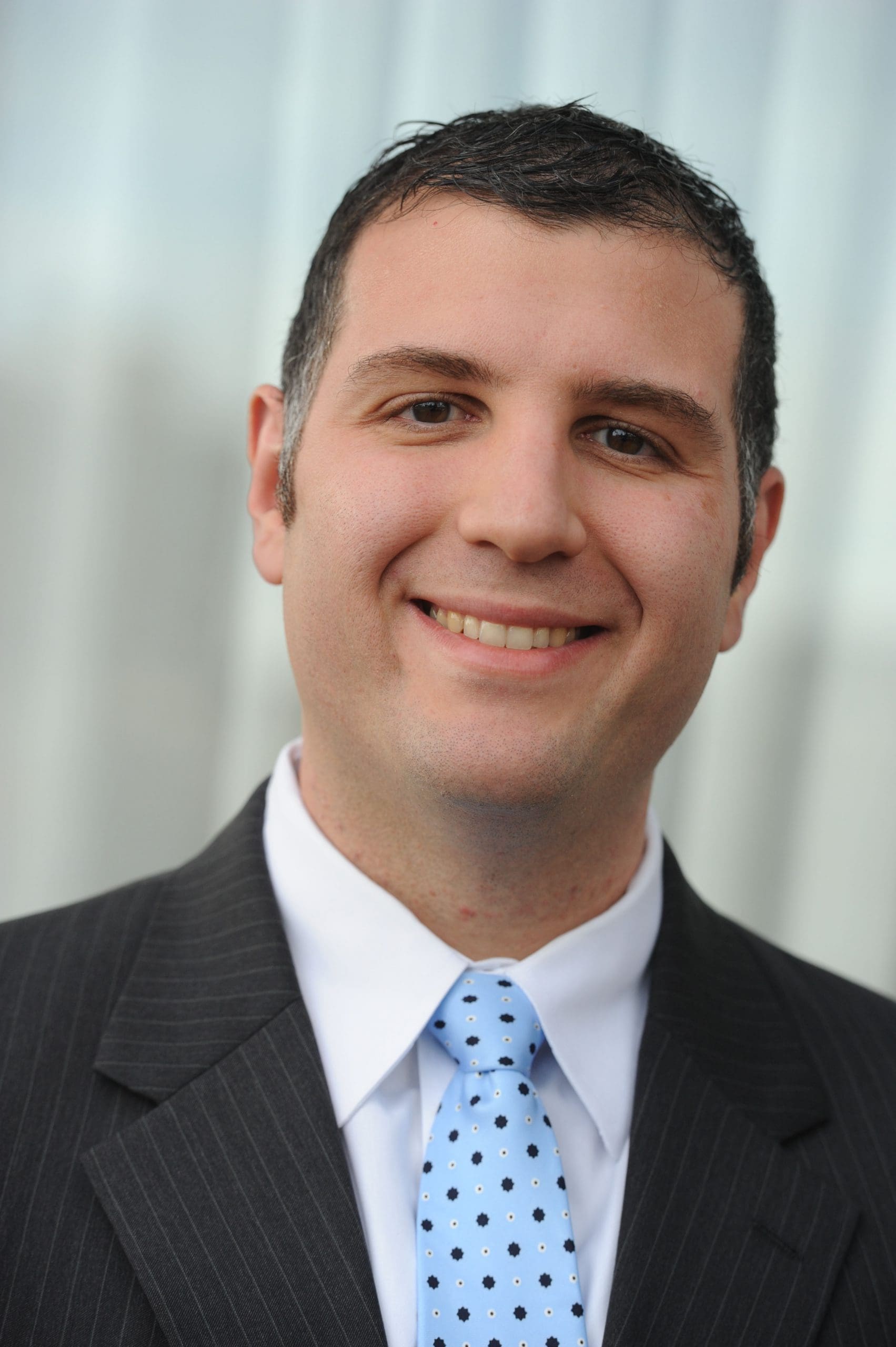 Man smiling, wearing shirt, tie and coat