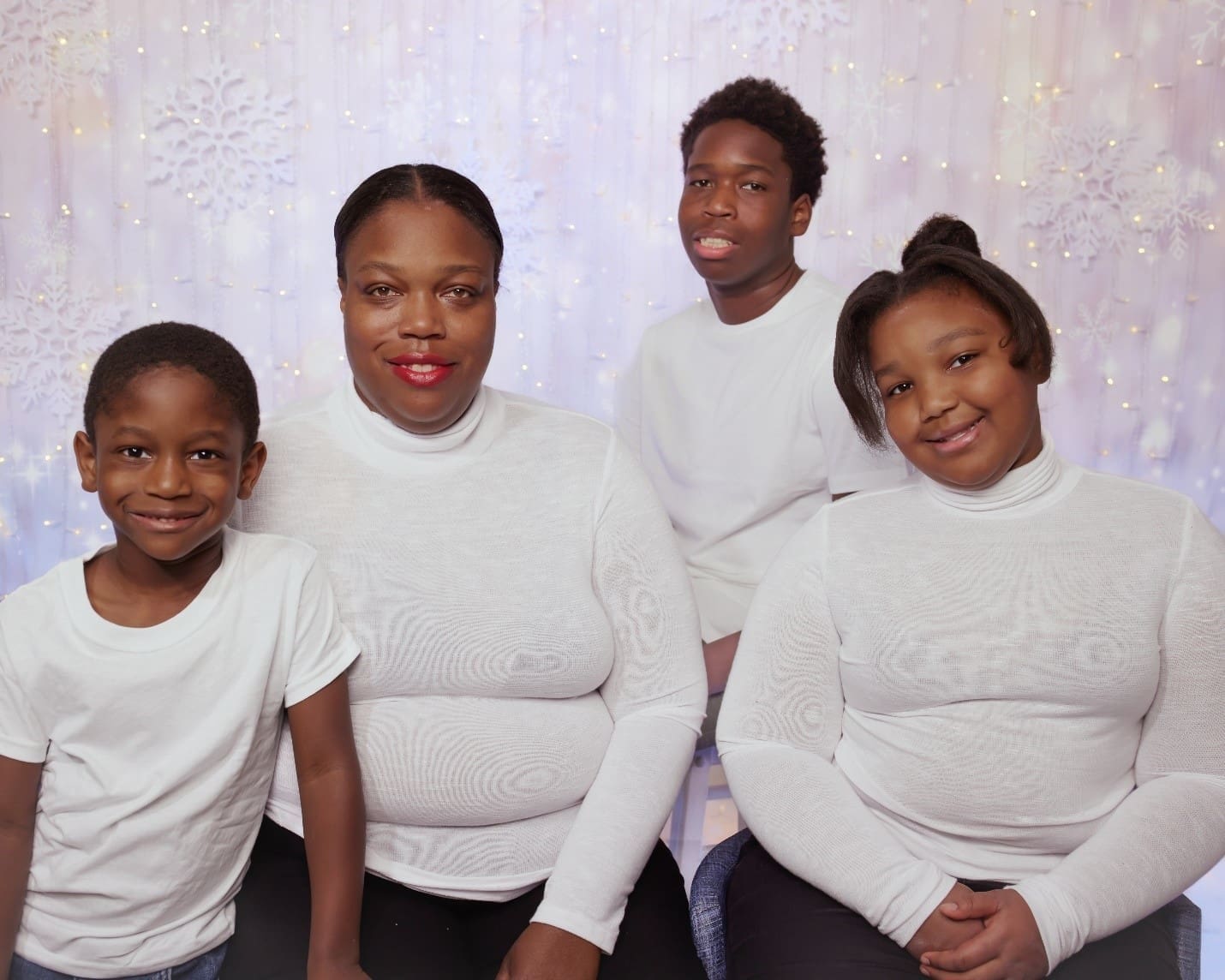 Four members of a family, dressed in white T-shirts, smiling for a photo.