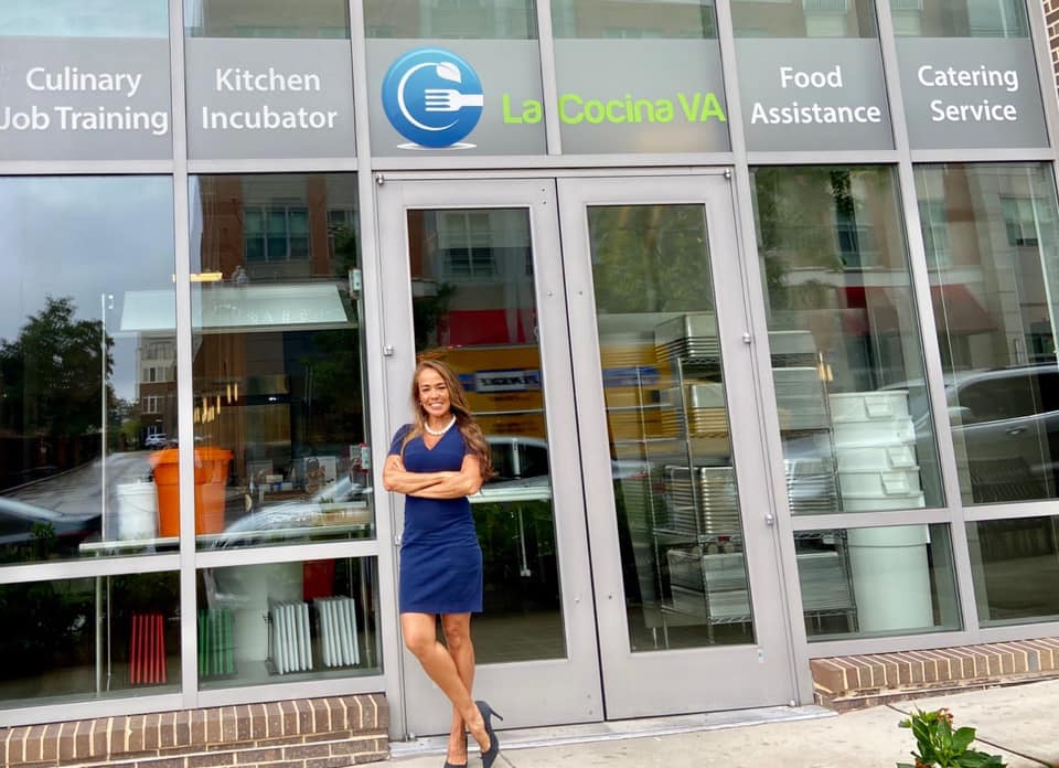 Woman wearing a blue dress, leaning on the door of the front of a café