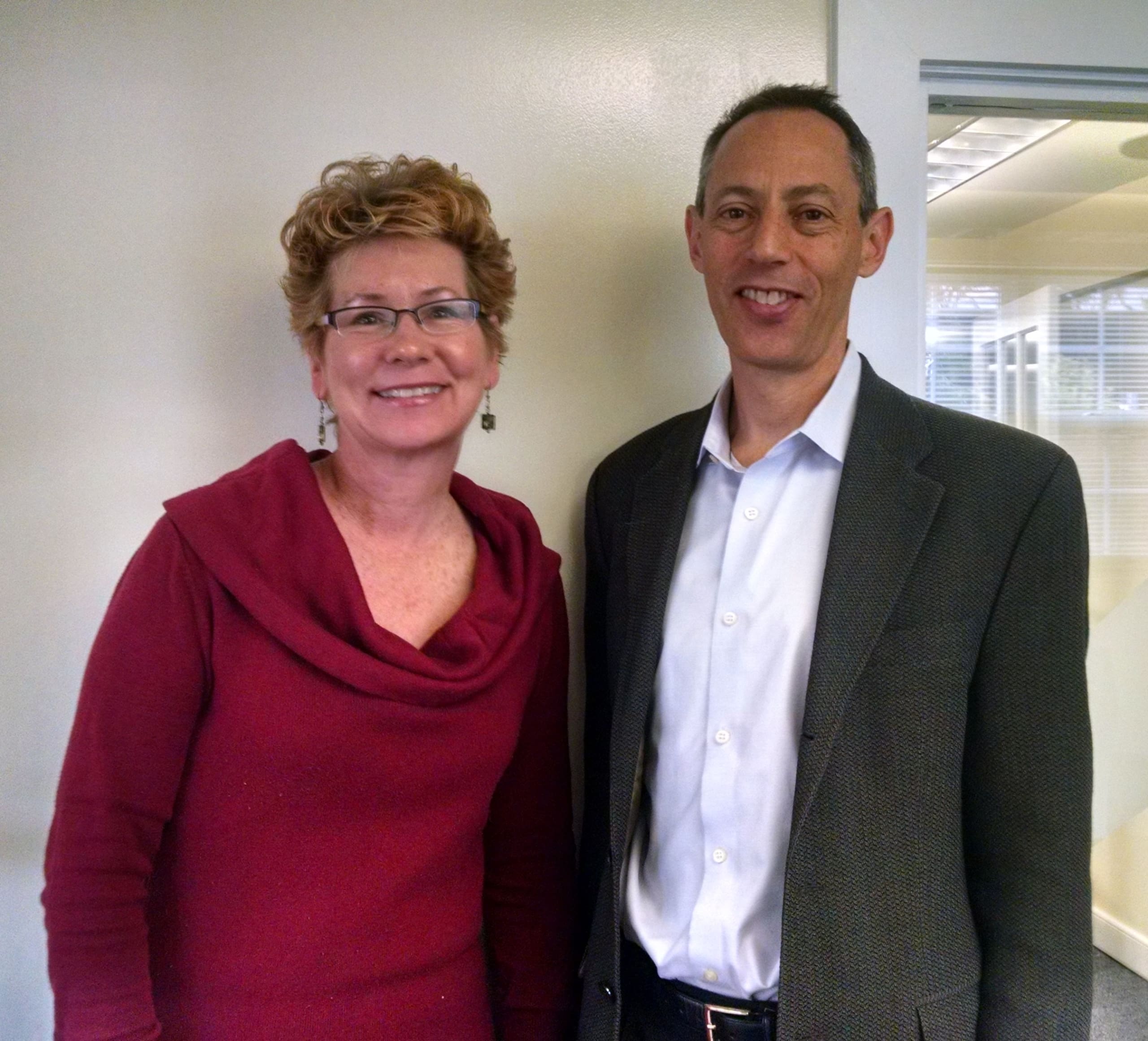 Smiling woman and man posing indoors in formal attire.
