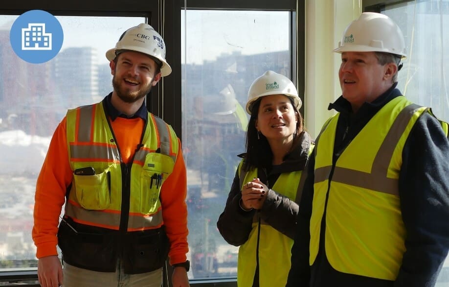 True-Ground-Strategic-Plan-Strategies@2x Construction workers and a project manager in safety vests and hard hats on-site