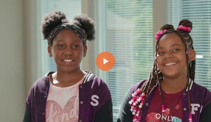 Screenshot of a video, where two girls are smiling.