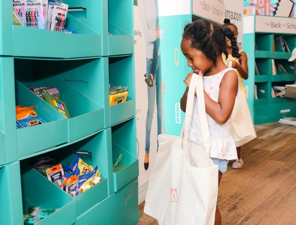 True-Ground-Ways-to-Give-Hero-Grid-Image-1@2x Young girl picking school supplies from a shelf